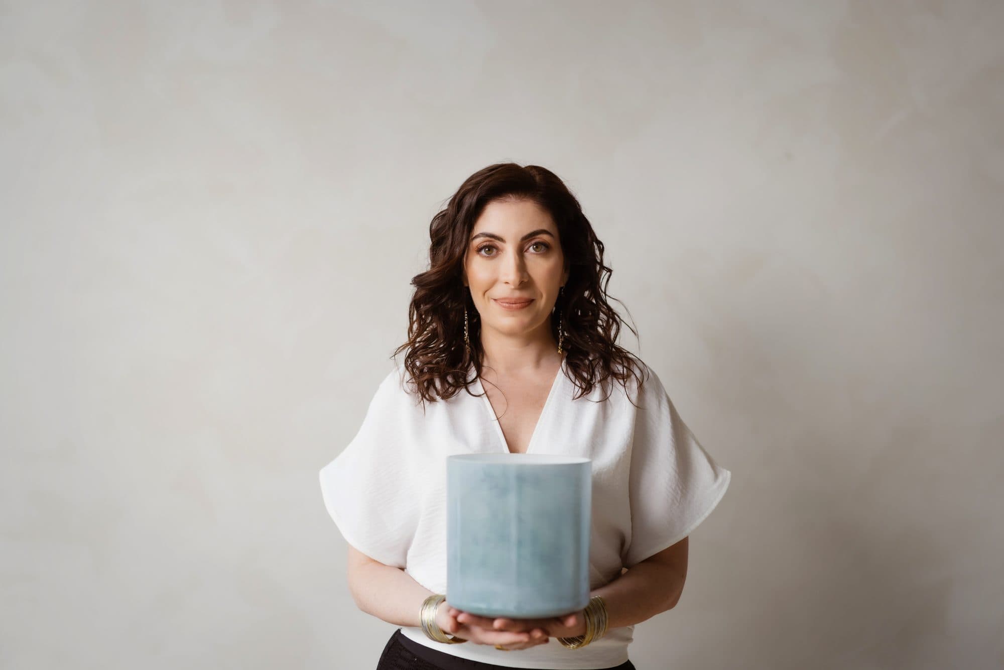 Jennifer Spencer holding a crystal singing bowl, looking directly at the camera