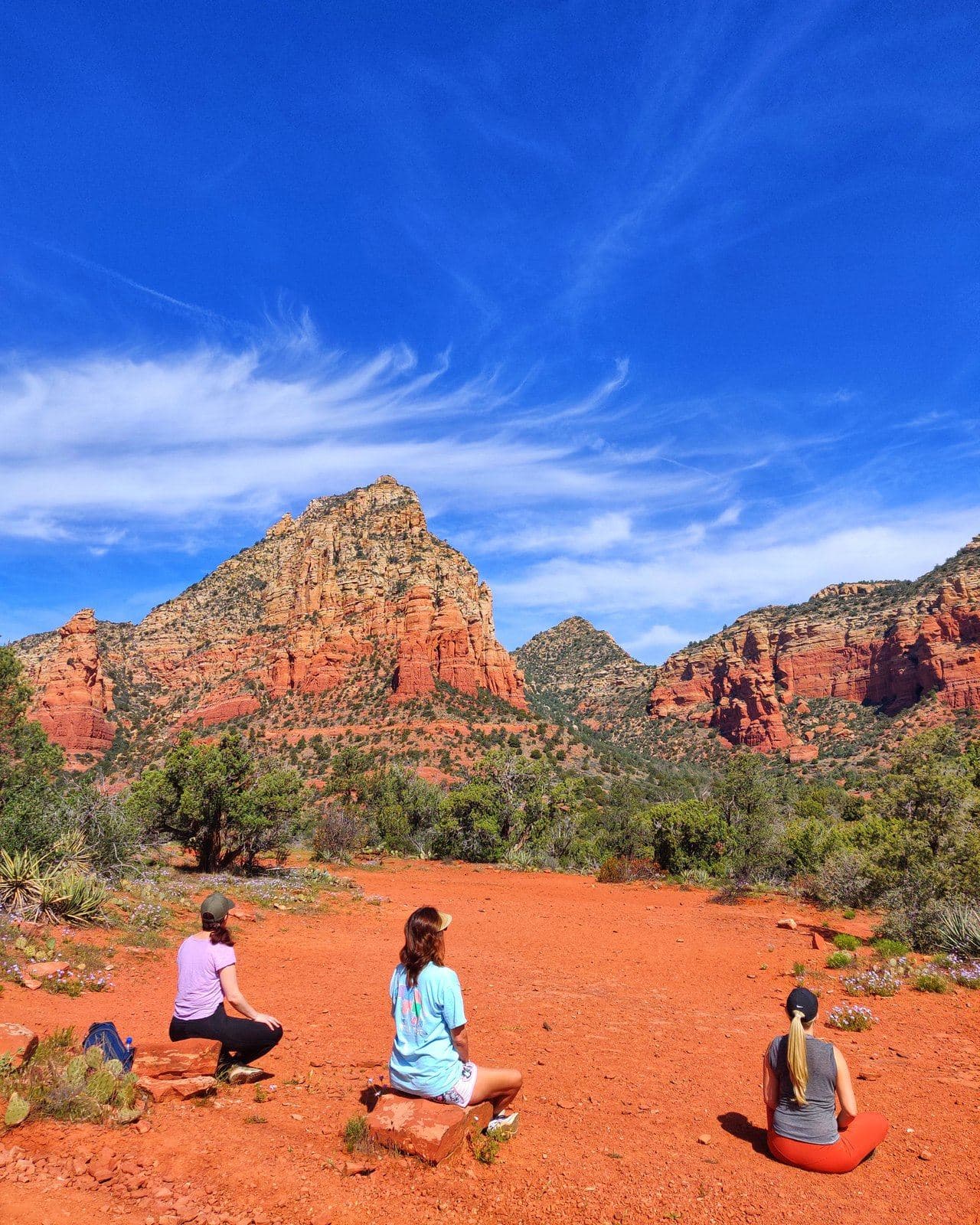 Retreat guests sitting on the red rock, looking out over the Sedona valley